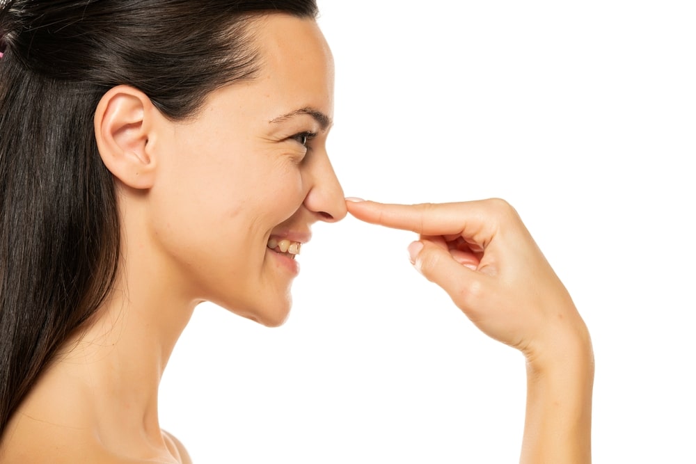 Young,Happy,Woman,Touches,Her,Nose,With,Her,Finger,On